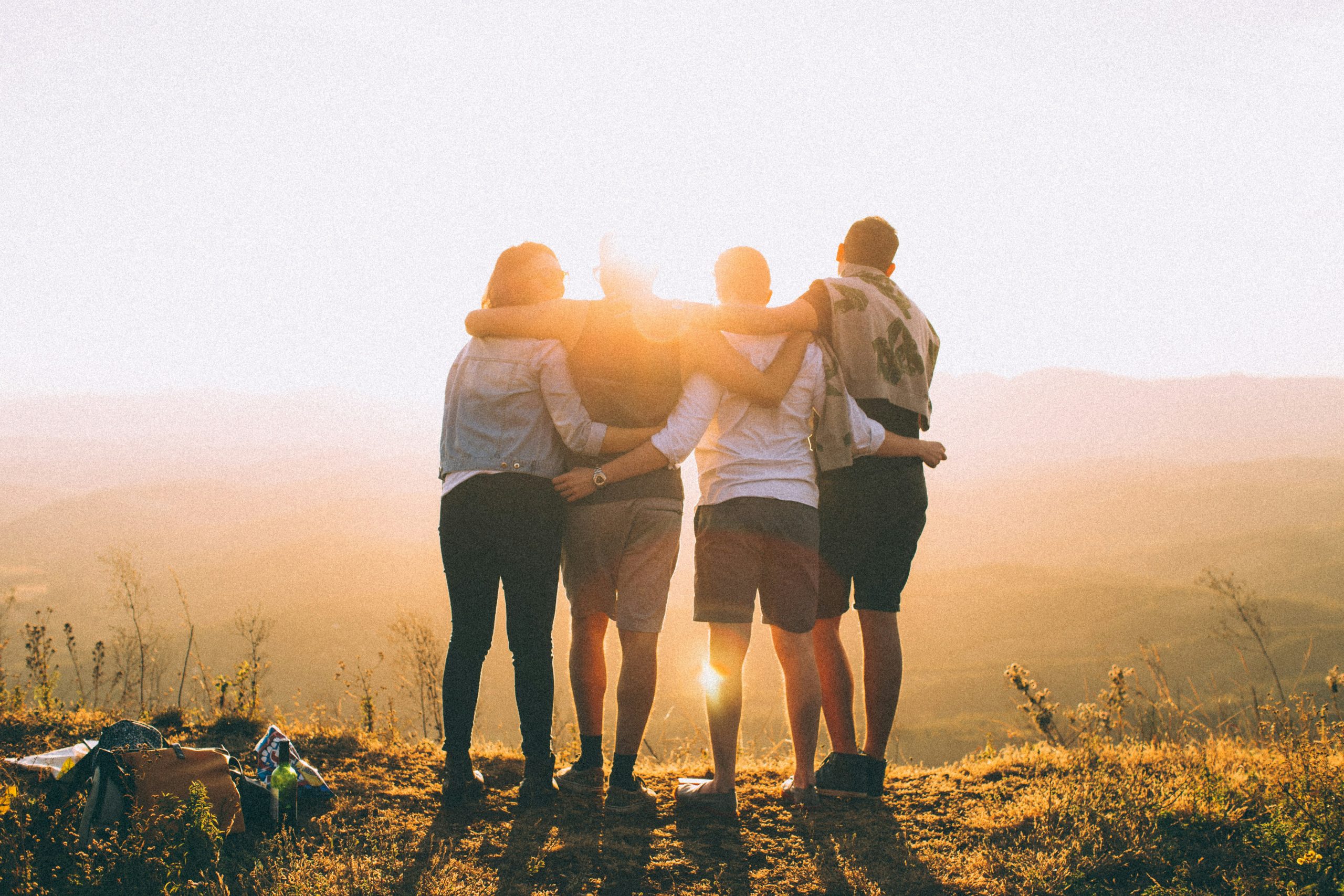 A group of people embrace while watching a sunset